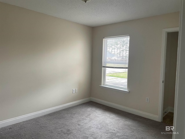 carpeted empty room featuring a textured ceiling and baseboards