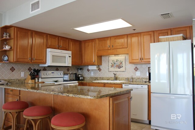 kitchen with backsplash, white appliances, sink, and a breakfast bar area