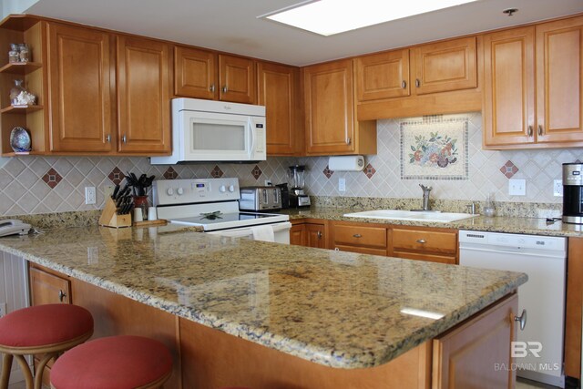 kitchen featuring kitchen peninsula, white appliances, and backsplash