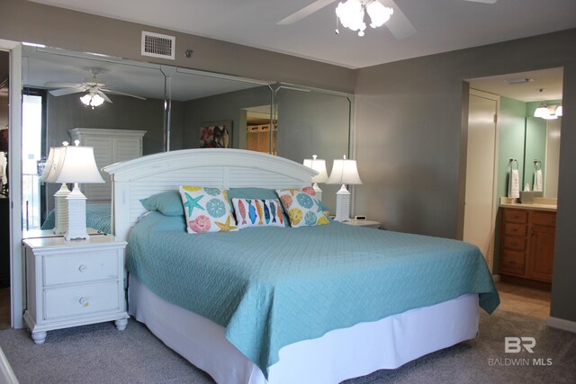 carpeted bedroom featuring ensuite bath and ceiling fan