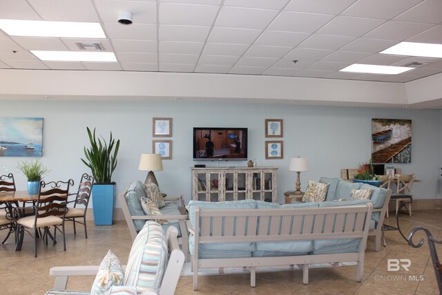 living room featuring a paneled ceiling and light tile patterned floors