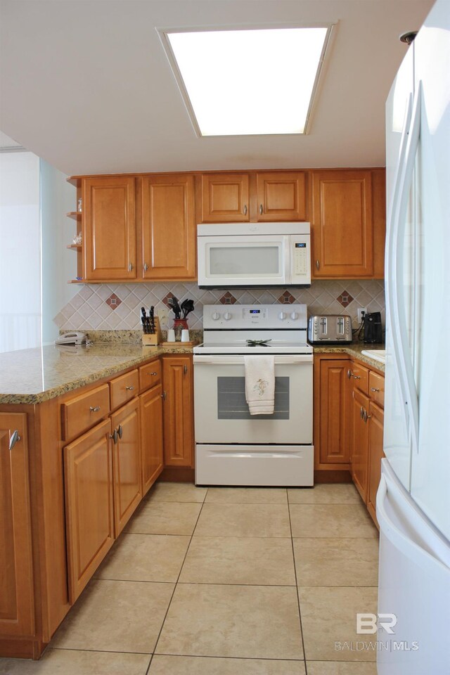 kitchen with kitchen peninsula, light stone countertops, tasteful backsplash, white appliances, and light tile patterned flooring