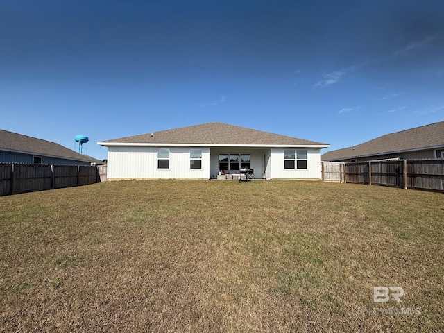 back of house with a fenced backyard and a yard