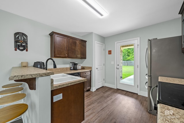 3931 Langley Ave, Foley, AL 36535 - kitchen with a kitchen bar, dark wood finished floors, a peninsula, dark brown cabinetry, and light countertops