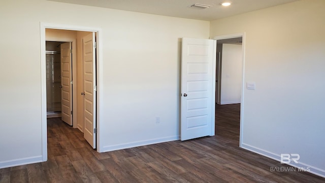 unfurnished bedroom featuring dark wood-style flooring, visible vents, and baseboards