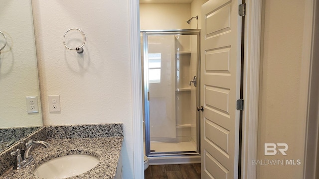 full bathroom featuring a shower stall, wood finished floors, and vanity