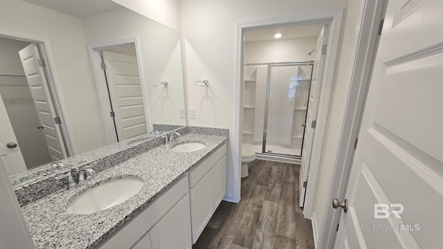 full bath featuring a sink, a shower stall, toilet, and wood finished floors