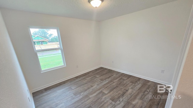 unfurnished room featuring a textured ceiling, dark wood-style flooring, and baseboards