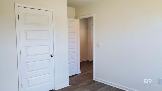 unfurnished bedroom featuring baseboards and dark wood-style flooring