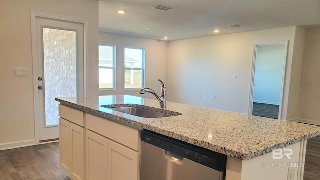 kitchen with a center island with sink, dark wood finished floors, dishwasher, light stone counters, and a sink