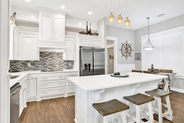 kitchen with a kitchen island, dark wood-type flooring, appliances with stainless steel finishes, and light countertops