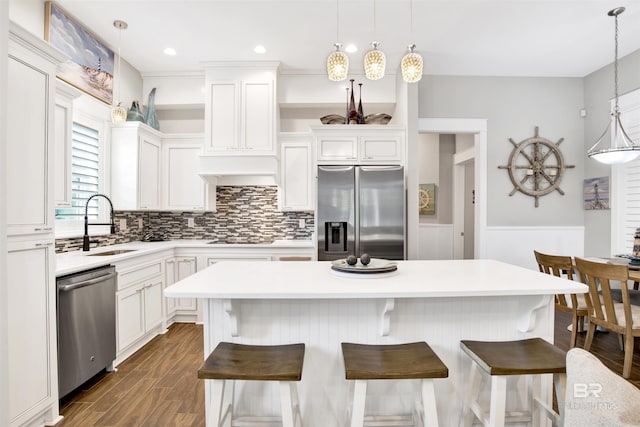 kitchen featuring a wainscoted wall, dark wood finished floors, a sink, light countertops, and appliances with stainless steel finishes