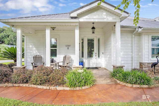 entrance to property with metal roof, a porch, and a standing seam roof