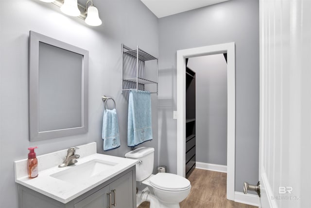 bathroom with toilet, vanity, baseboards, and wood finished floors