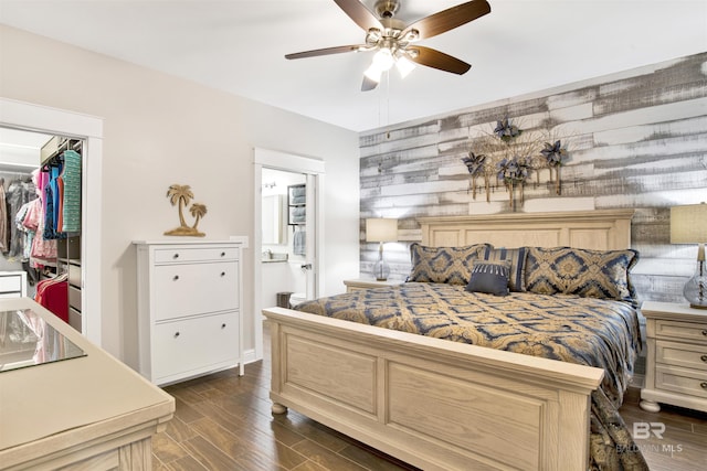 bedroom featuring a spacious closet, connected bathroom, a closet, a ceiling fan, and dark wood-style flooring