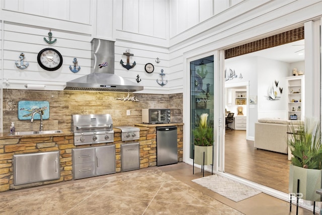 kitchen with fridge, a sink, and wall chimney range hood