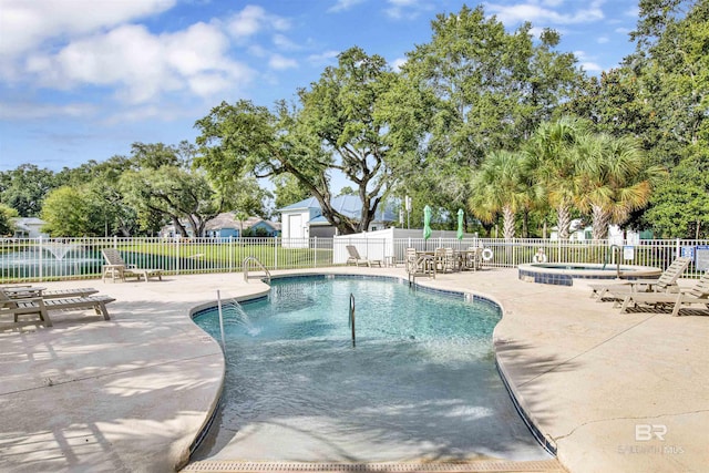 pool with a patio, a community hot tub, and fence