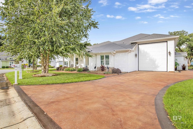 view of front of home with metal roof, driveway, a garage, and a front yard