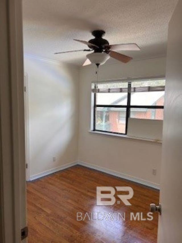 spare room featuring baseboards, a textured ceiling, wood finished floors, and a ceiling fan