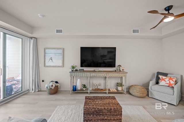 living area featuring a ceiling fan, visible vents, and wood finished floors