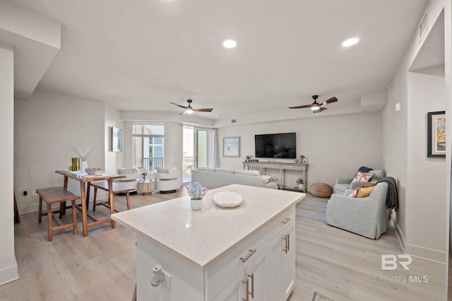 kitchen featuring white cabinets, ceiling fan, a center island, light wood-type flooring, and recessed lighting