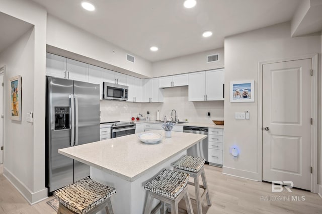 kitchen with visible vents, stainless steel appliances, a sink, and a kitchen breakfast bar