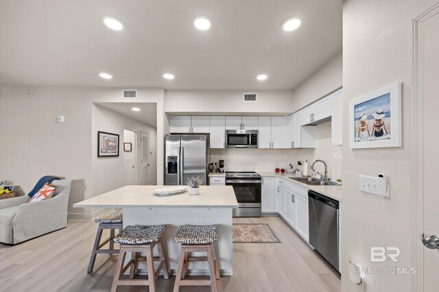 kitchen with visible vents, stainless steel appliances, a sink, and a center island