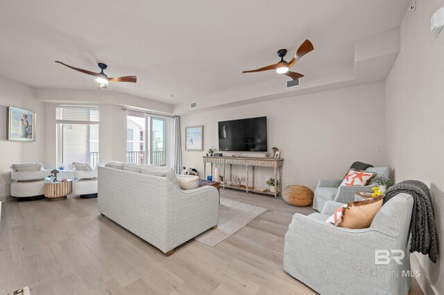 living area featuring ceiling fan, light wood finished floors, and visible vents