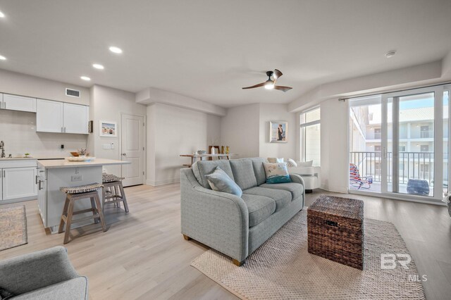 living area with light wood-type flooring, visible vents, ceiling fan, and recessed lighting