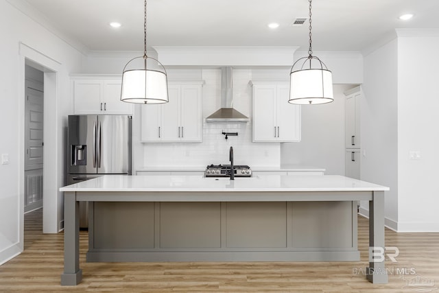 kitchen with wall chimney exhaust hood, ornamental molding, light countertops, and decorative backsplash