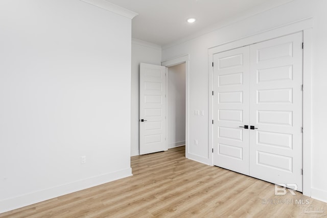 unfurnished bedroom featuring baseboards, ornamental molding, light wood-style floors, a closet, and recessed lighting