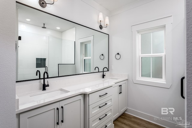 full bath with double vanity, wood finished floors, a sink, and baseboards