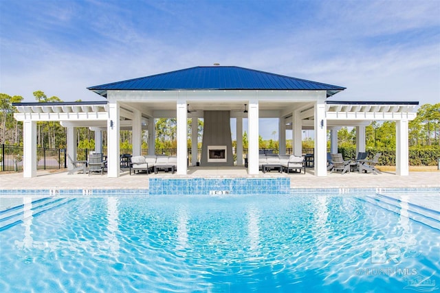 pool featuring an outdoor living space with a fireplace, a patio area, ceiling fan, fence, and a pergola