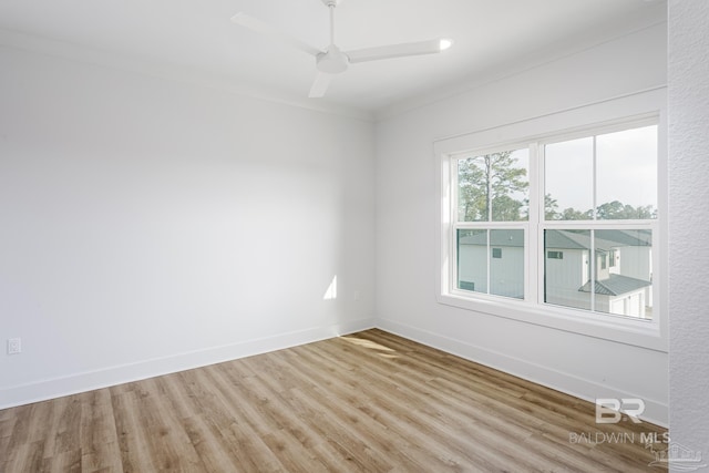 empty room with baseboards, ornamental molding, a ceiling fan, and light wood-style floors