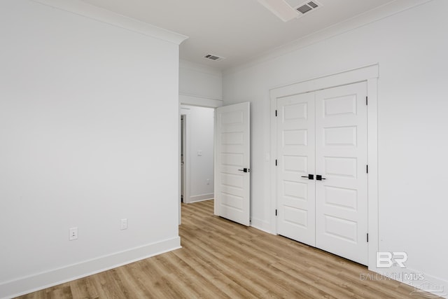 unfurnished bedroom featuring light wood-type flooring, baseboards, visible vents, and crown molding