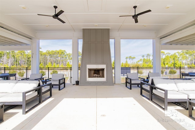 view of patio featuring a ceiling fan, fence, and an outdoor living space with a fireplace