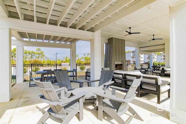 view of patio / terrace with ceiling fan, a fireplace, fence, and outdoor dining space