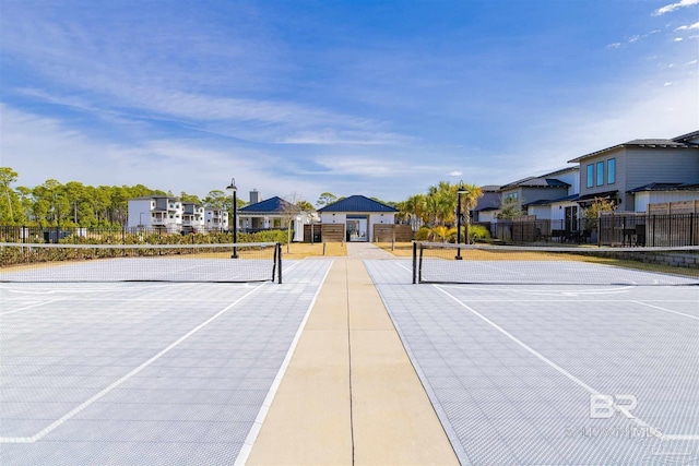 view of tennis court featuring a residential view and fence