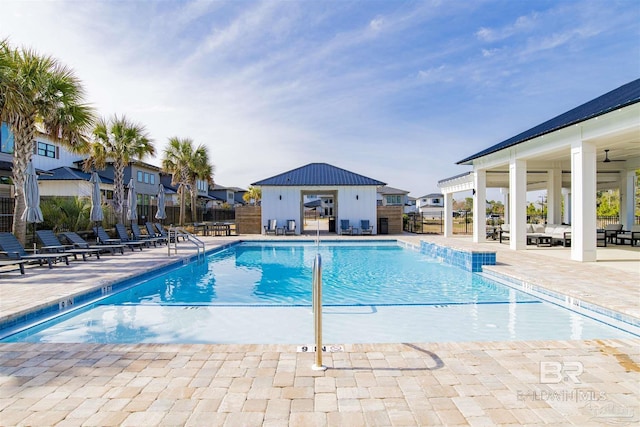 pool featuring a patio area, fence, and an outdoor structure