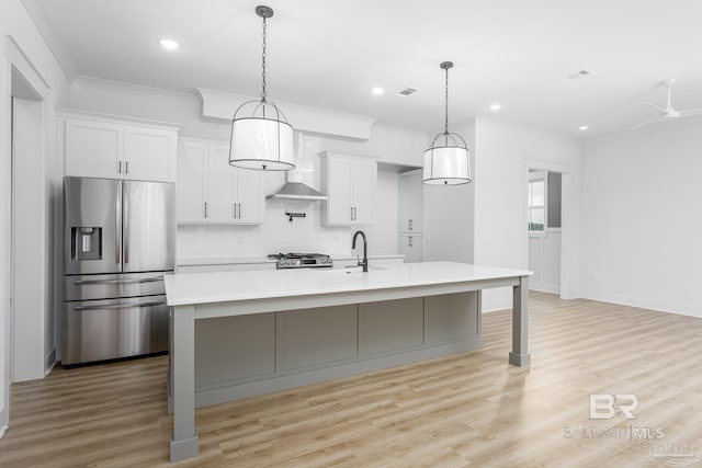 kitchen with light countertops, white cabinetry, a sink, an island with sink, and stainless steel fridge with ice dispenser