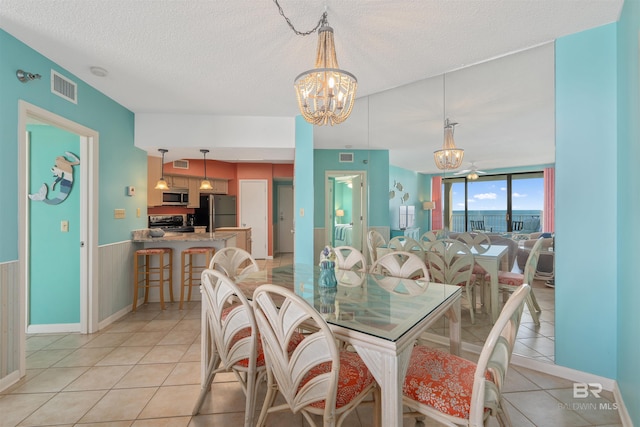 dining area with an inviting chandelier, a textured ceiling, and light tile flooring