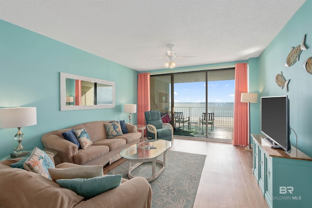 living room featuring ceiling fan, floor to ceiling windows, a textured ceiling, and light hardwood / wood-style floors