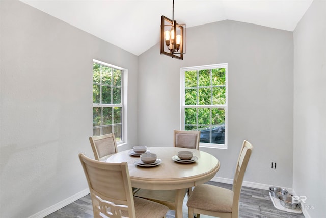 dining space featuring vaulted ceiling, wood-type flooring, and an inviting chandelier