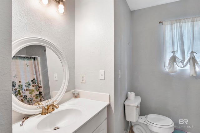 bathroom with toilet and vanity with extensive cabinet space