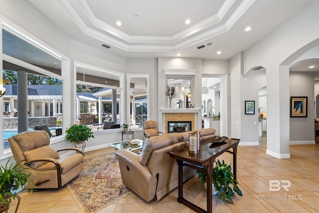 tiled living room featuring crown molding, a high end fireplace, and a raised ceiling