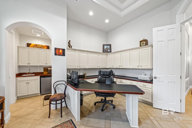 tiled home office with a high ceiling, built in desk, crown molding, and sink