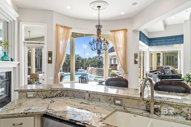 kitchen with plenty of natural light, light stone counters, sink, and a chandelier