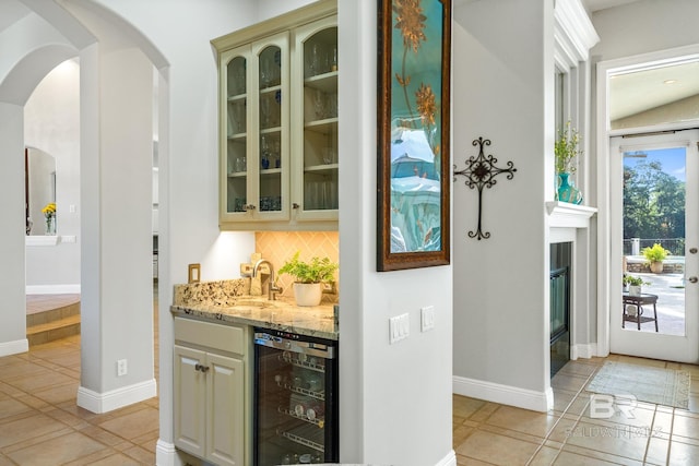 bar with vaulted ceiling, wine cooler, light tile patterned floors, sink, and light stone counters