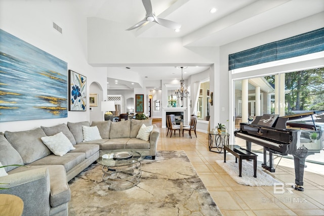 living room with a towering ceiling, ceiling fan with notable chandelier, and light tile patterned flooring