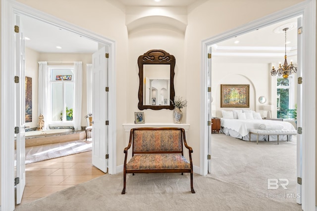 hallway featuring light colored carpet and a notable chandelier